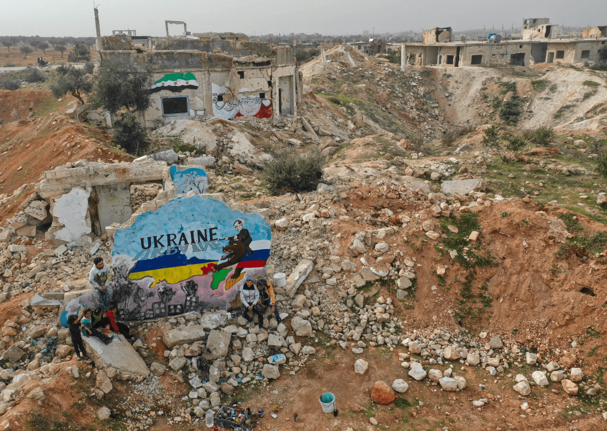 Um mural pintado por artistas sírios para protestar contra a operação militar da Rússia na Ucrânia, em meio à destruição na cidade de Binnish, controlada pelos rebeldes, na província de Idlib, noroeste da Síria, em 24 de fevereiro de 2022.