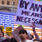 Um manifestante segura um cartaz no comício All Out for Palestine [Todos na rua pela Palestina], na Times Square.