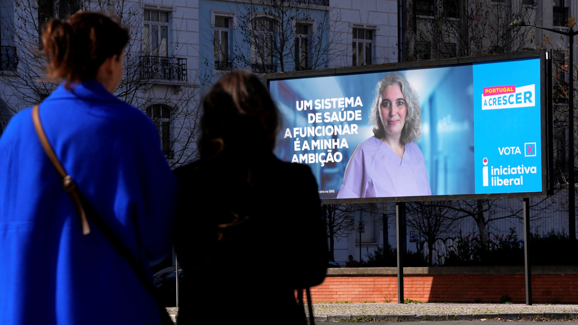 Pessoas observam um outdoor da campanha eleitoral em Lisboa.