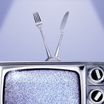 An old TV with a fuzzy screen and an antenna made from a fork and knife.