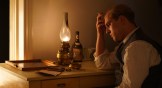 A still from the movie depicting Bonhoeffer sitting and thinking at his desk.