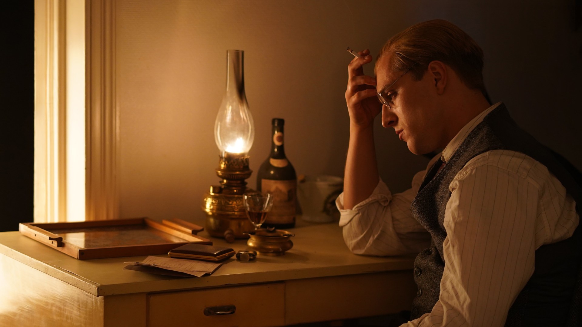 A still from the movie depicting Bonhoeffer sitting and thinking at his desk.