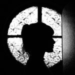 Silhouette of a young woman in front of cross-shaped window lighting.
