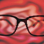 A fuzzy distorted image of glasses on a red background.