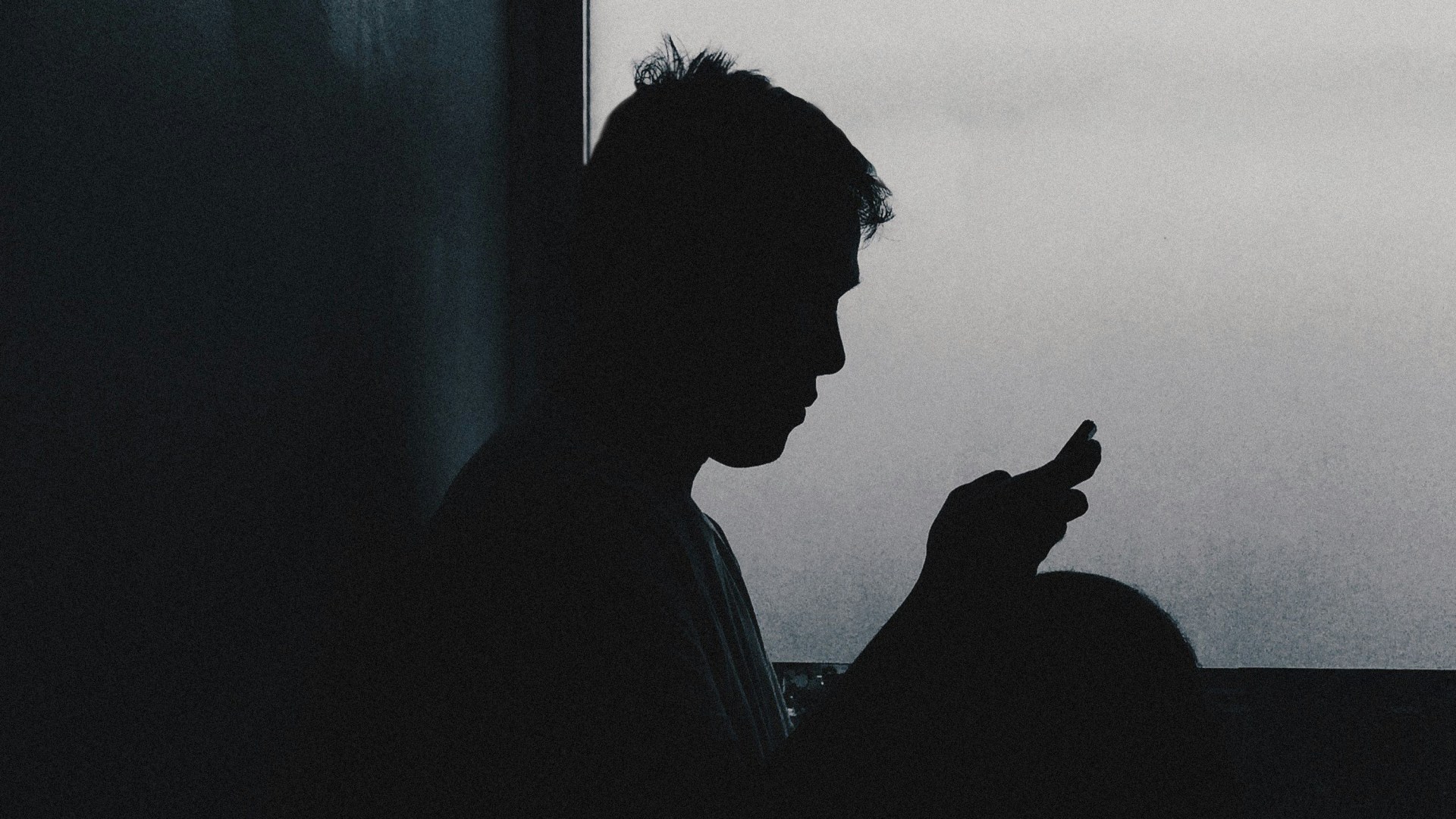 A man on his phone in shadow.