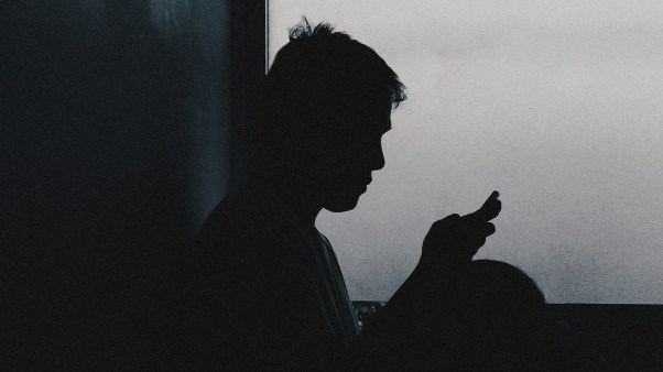 A man on his phone in shadow.